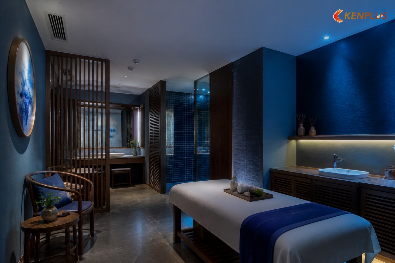 Phòng spa xanh navy, vách lam gỗ, gạch mosaic xanh khu tắm và ghế gỗ chờ